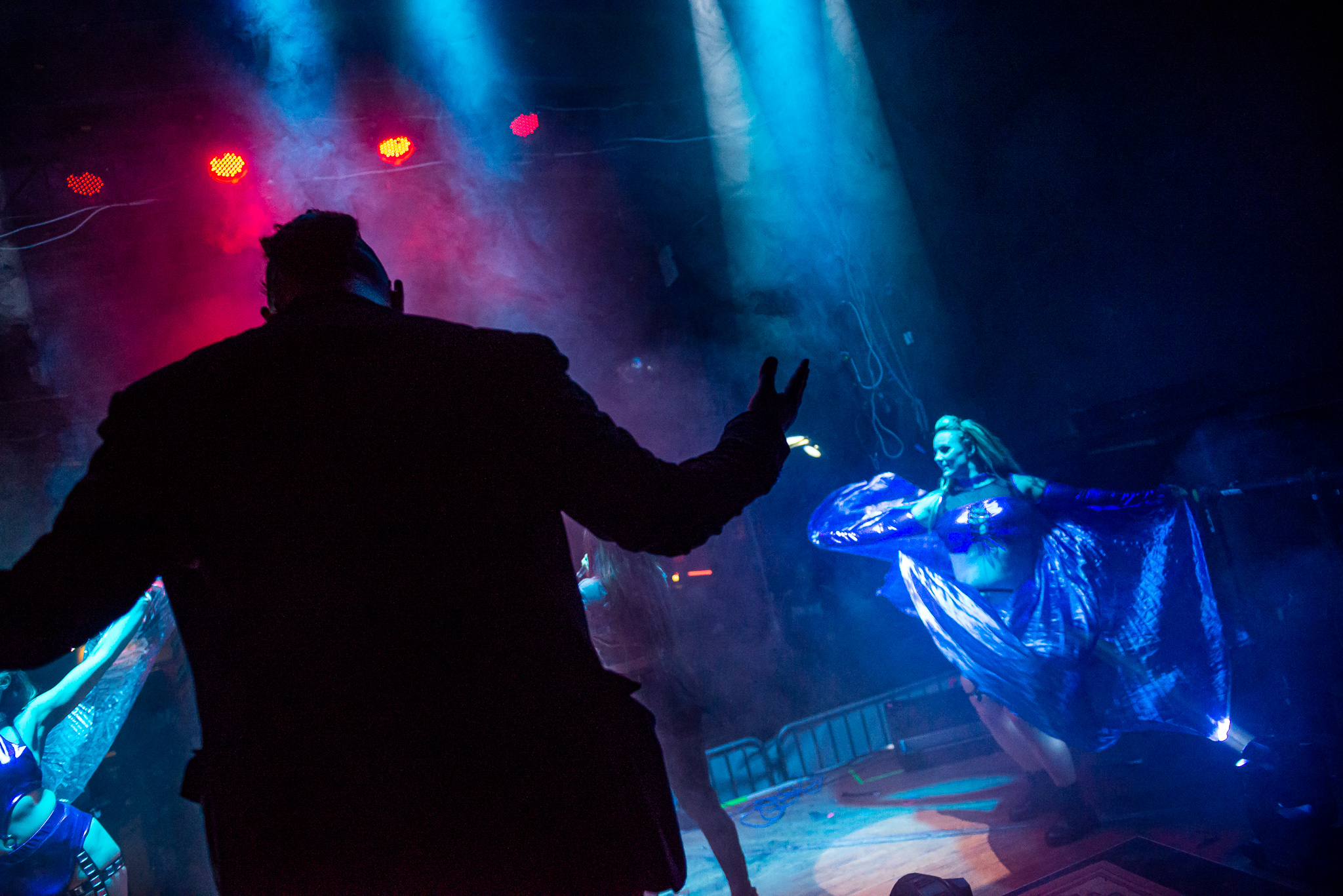 Live shot from behind Mike Midas' black jacket. Singer and dancers in the background. Photo by Sami Hinkkanen.